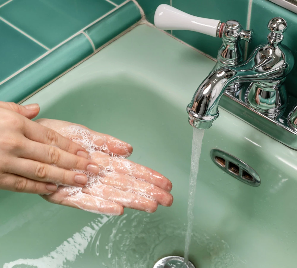 person washing hands in a green sink